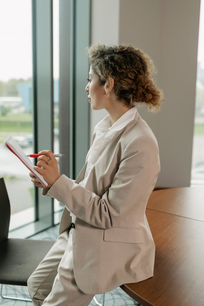 gallery-1 Businesswoman in suit writing notes in an office environment.